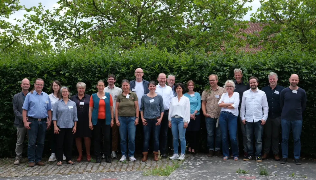 Mehrere Personen in einer Reihe vor einer Hecke. Die Personen sind die Teilnehmer der Veranstaltung.